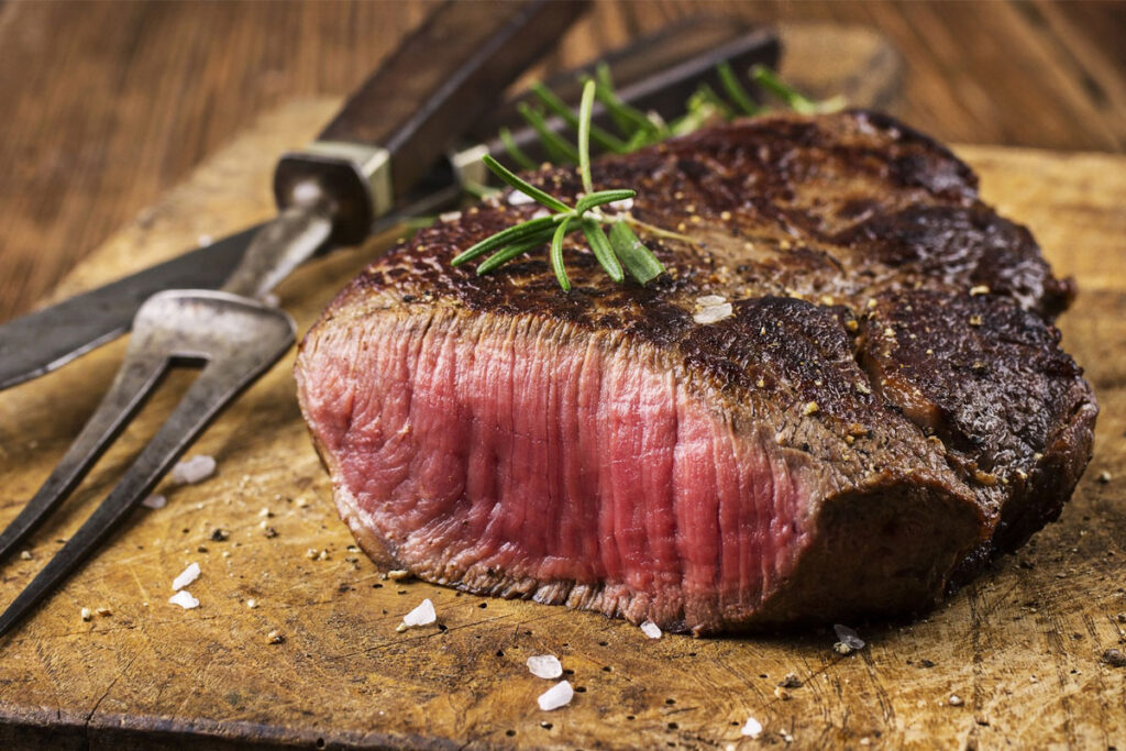 Rare steak sliced on a wooden board with rosemary at The Plough