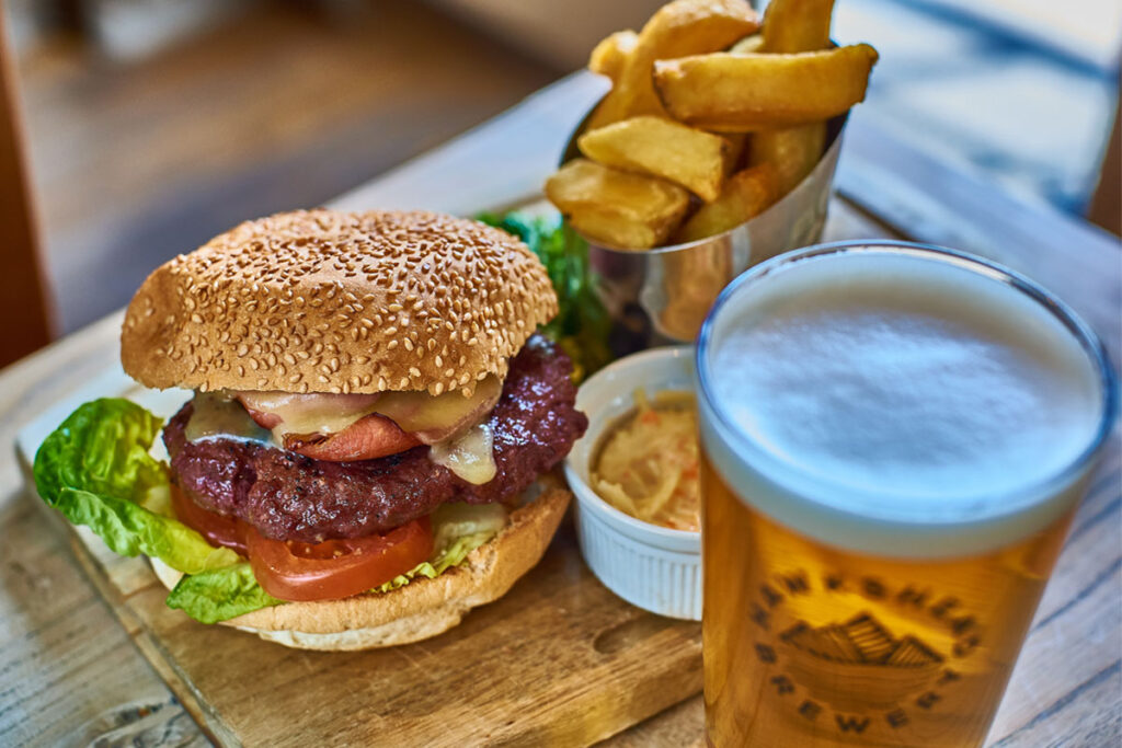 Cheeseburger with bacon, chips and a pint of ale on a wooden board at The Plough