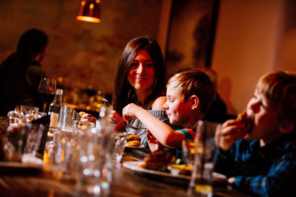 A mum and two boys eating together at a table at The Plough